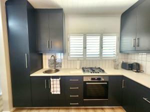 a kitchen with dark blue cabinets and a sink at Welgelegen Self Catering in Malmesbury