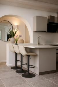 a kitchen with two white bar stools and a sink at Casabaja in Baja Sardinia