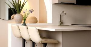 a kitchen with a counter with white chairs and a sink at Casabaja in Baja Sardinia