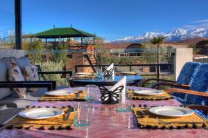 Ein Tisch mit Tellern und Gläsern auf einer Terrasse mit Bergblick in der Unterkunft The Ranch Resort in Marrakesch