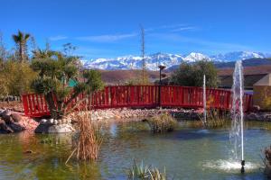 Eine rote Brücke über einen Teich mit Springbrunnen in der Unterkunft The Ranch Resort in Marrakesch