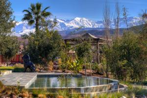 Eine Hundestatue in einem Garten mit Bergen im Hintergrund in der Unterkunft The Ranch Resort in Marrakesch