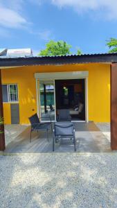 a yellow house with two chairs and a patio at Emma modern suite in Kourou