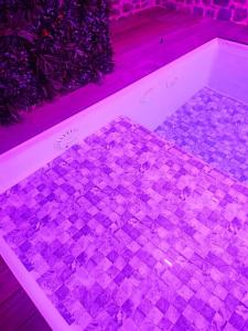 a room with a mosaic floor with purple lights at Jacuzzi XXL avec La Rouyonnaise in Tinténiac