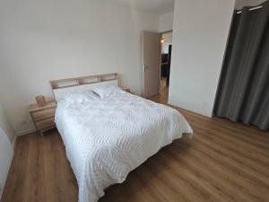 a bedroom with a white bed and a wooden floor at La Parenthèse du Châtelet in Saint-Étienne-de-Valoux