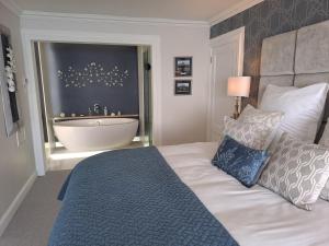 a bedroom with a tub and a bed and a bath room at Boutique Inn - Azure in Gordonʼs Bay