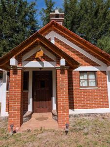 a small brick house with a brown door at Del Cortes Cabañas in Velasco