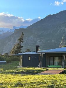 a black house with mountains in the background at Límite Sur Lodge in Trevelín