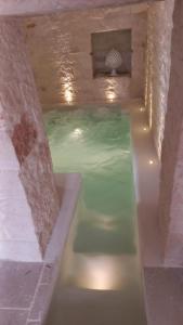 a swimming pool with green water in a building at Trulli Fichi Luxury Trullo with Private Spa and Saltwater Pool in Santa Lucia