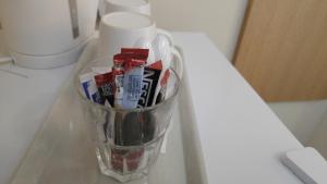 ロンドンにあるシティー ビュー ホテル ストラットフォードのカウンターに備わるガラスのカップ(歯ブラシと歯磨き粉付)
