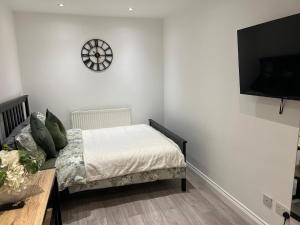 a bedroom with a bed and a clock on the wall at Modern Studio flat with free parking in Langley Marish