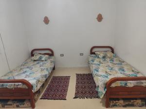 two beds in a room with two rugs at Dar Karim in Midoun