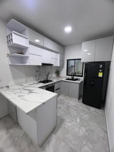 a kitchen with white cabinets and a black refrigerator at Villa Sabanilla Casa bifamiliar campestre con piscina privada Aire acondicionado Tranquilidad total in Puerto Colombia