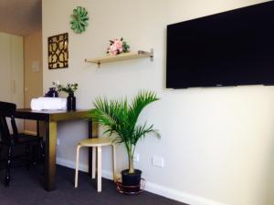 a room with a desk and a tv on a wall at Ivy and Roses Boutique Apartments in Canberra