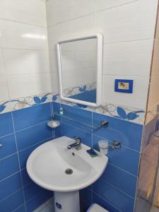 a blue tiled bathroom with a sink and a mirror at Dar Karim in Midoun +5 photos