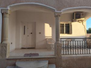 a porch with a white door and a fence at Dar Karim in Midoun