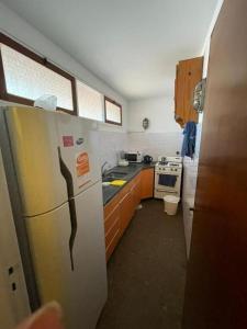 a small kitchen with a refrigerator and a stove at PH con cochera cubierta cerca de la playa in Villa Gesell