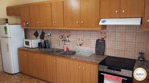 a kitchen with wooden cabinets and a white refrigerator at Anastasia's Apartment ΛΑΥΡΙΟ in Lavrio