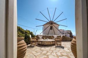 a stone patio with a windmill in the background at Traditional Windmill House , Chora Serifos in Serifos Chora