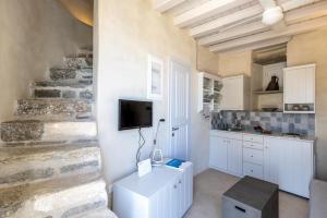 a kitchen with white cabinets and a tv on a wall at Traditional Windmill House , Chora Serifos in Serifos Chora +39 photos
