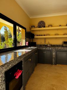 a large kitchen with black cabinets and a large window at Dar Laydam in Aït Zat