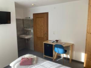 a bedroom with a bed and a desk and a sink at Pension Haus Georg in Westendorf