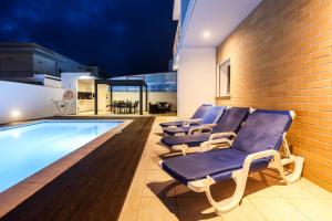 a row of lounge chairs next to a swimming pool at Nazare House4you in Nazaré