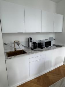a white kitchen with a sink and a microwave at La suite du parc 2 in Nancy