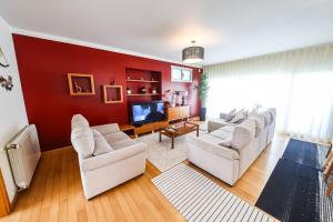 a living room with white chairs and a red wall at Nazare House4you in Nazaré