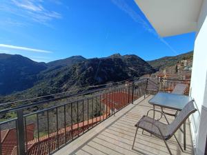 a balcony with a table and chairs and mountains at Νύμφη Ηχώ, Θέα στα βουνά κάτω από το Ρολόι in Dimitsana