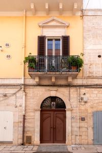 a building with a balcony and a wooden door at Le Gravinelle - Apulia Houses & Flats in Ruvo di Puglia