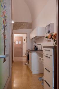 a kitchen with white cabinets and a tile floor at Le Gravinelle - Apulia Houses & Flats in Ruvo di Puglia
