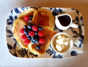 a plate with pancakes and berries and a cup of coffee at Lily Pad Apartment in Motueka