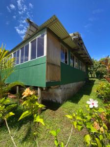 a green and wooden house with some flowers at Hare Sunset Rapa Nui in Hanga Roa