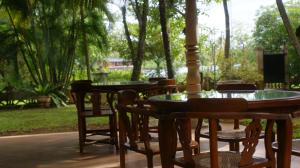 two tables and chairs with trees in the background at Dedduwa Boat House in Bentota