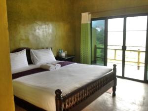 a bedroom with a bed and a large window at Baan Ruam Cha in Mae Salong