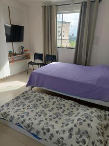 ein Schlafzimmer mit einem lila Bett und einem Fenster in der Unterkunft Flat da Lua in Viçosa