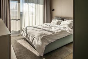 a bedroom with a bed with white sheets and a window at Luxury Blue Apartment in Satu Mare
