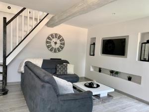 a living room with a couch and a clock at Cocon de Fontaine in La Madeleine-de-Nonancourt