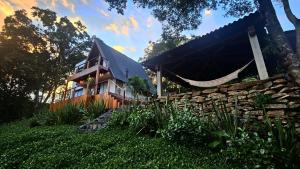 a house with a fence and a stone wall at Cabana Espelho da Lua in Itá
