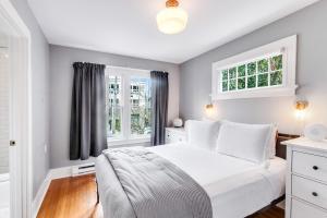 a bedroom with a white bed and two windows at Montlake Hideaway in Spite House in Seattle