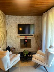 a living room with two chairs and a tv on a stone wall at Cabana Espelho da Lua in Itá