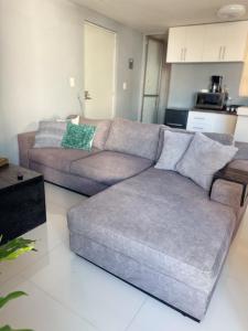 a grey couch in a living room with a kitchen at Cómodo departamento in Santa María Coronanco