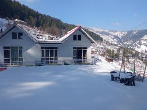 a house with snow in front of it at Mistymountaincottage in Shimla