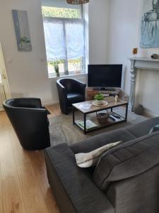 a living room with a couch and chairs and a tv at HoLiDaYs in Arques
