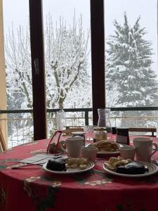 a table with a red table cloth with plates of food at Central near station in Bardonecchia
