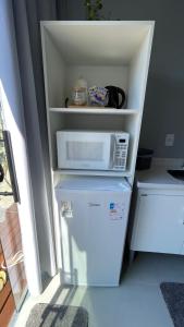 a microwave sitting on top of a refrigerator at Studio 02 Container Aeroporto in Florianópolis