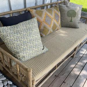 a wooden bench with pillows on a porch at Seaside Cabin With Ocean View In Odsherred in Nyrup