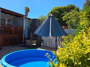 a patio with a blue pool and an umbrella at 35 Amanda - Durbanville in Cape Town +23 photos