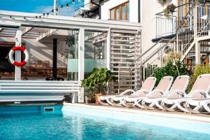 a pool with lounge chairs and a swimming pool at Orbisa Bis w cenie Basen podgrzewany Sauna Jacuzzi Rowery Parking Klimatyzacja Opcja śniadań in Łeba